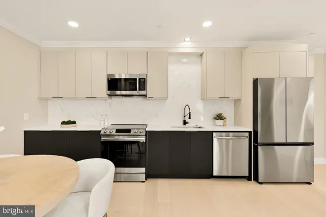 a kitchen with stainless steel appliances a stove a sink a microwave a refrigerator and cabinets