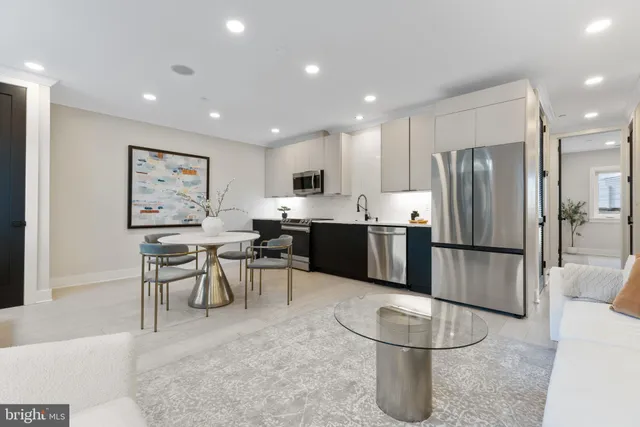 a kitchen with stainless steel appliances granite countertop a refrigerator a stove a sink a dining table and chairs