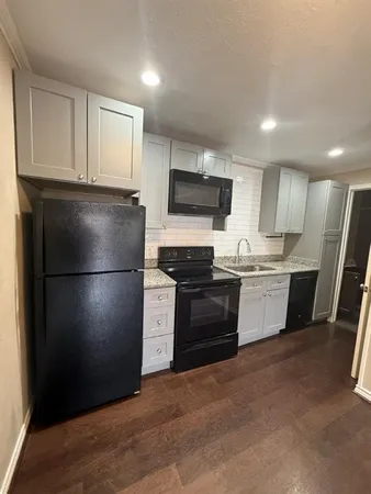 a kitchen with a refrigerator a microwave a sink and cabinets