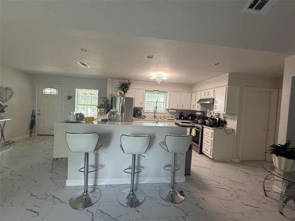 968 Red Town Road Elgin, TX 78621 - Photo 5 of 36 Kitchen featuring light marble finish floors, a breakfast bar, white cabinetry, and recessed lighting