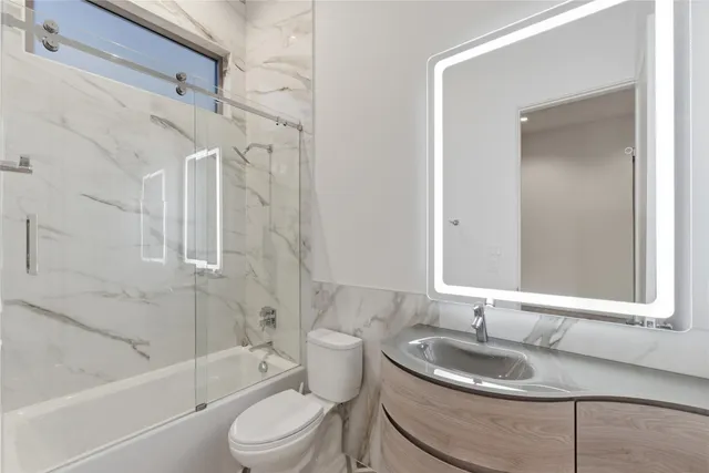 a bathroom with a granite countertop sink toilet a mirror and bathtub