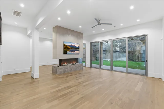 a view of an empty room with floor to ceiling window and ceiling fan