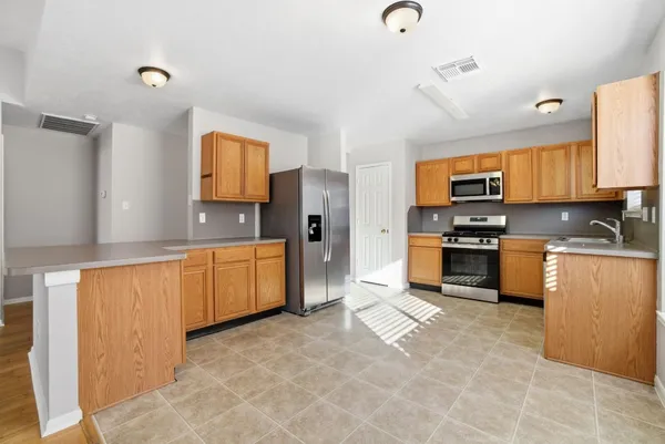 a kitchen with stainless steel appliances a stove a sink a microwave a refrigerator a counter top space and cabinets