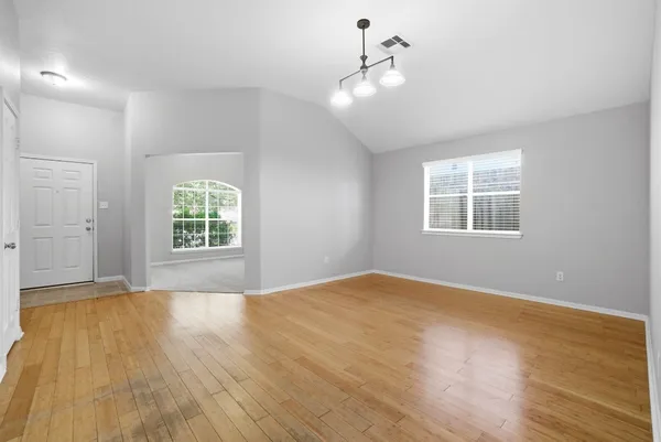 a view of an empty room with a window and wooden floor