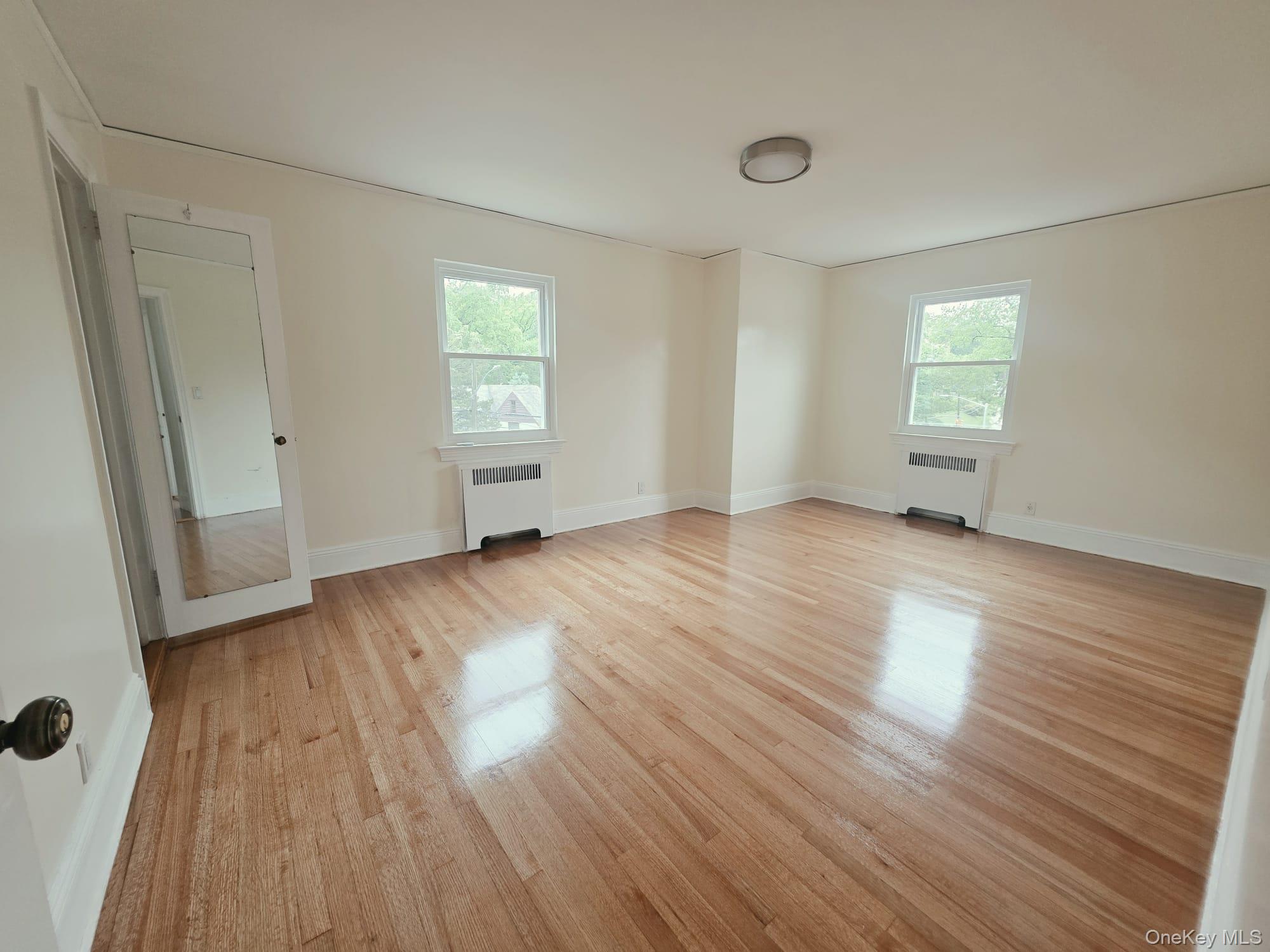 180-15 Dalny Road Queens, NY 11432 - Photo 8 of 10 an empty room with wooden floor and windows