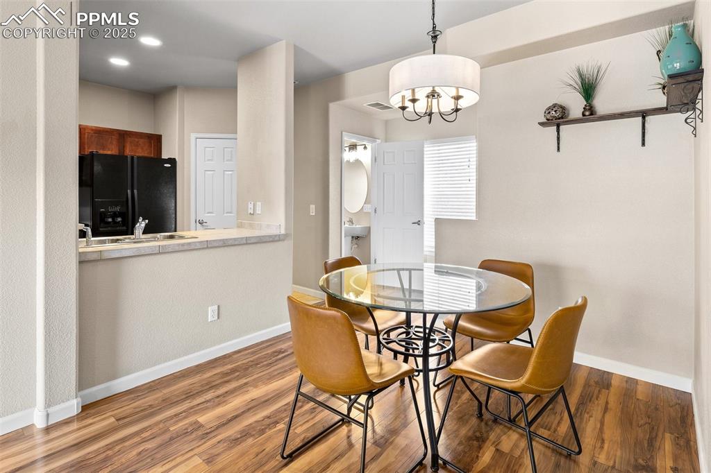 4073 Flash Point Colorado Springs, CO 80907 - Photo 7 of 20 a dining room with wooden floor a chandelier a wooden table and chairs