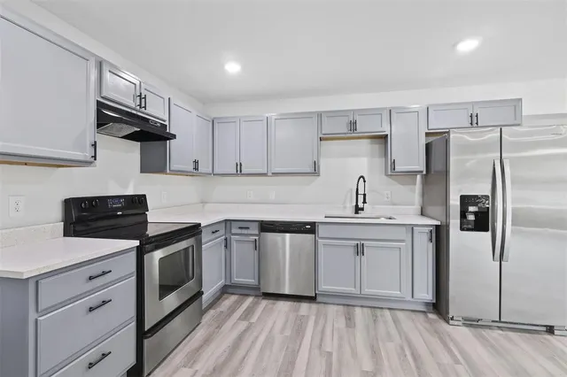 a kitchen with stainless steel appliances a sink cabinets and wooden floor