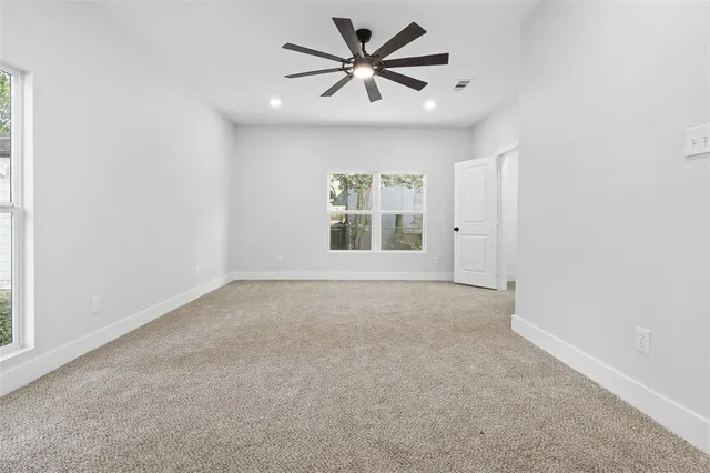 an empty room with windows and a ceiling fan