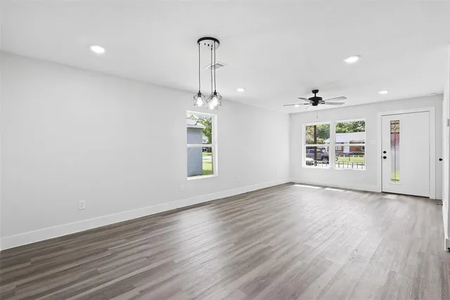 an empty room with wooden floor chandelier and windows