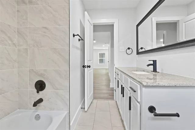 a bathroom with a granite countertop sink a mirror and a bathtub
