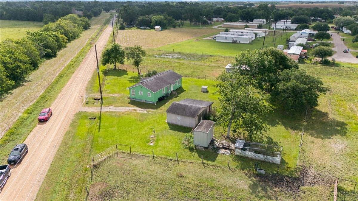 765 Norcross Road Wallis, TX 77485 - Photo 39 of 42 This photo shows a charming rural property with a few outbuildings, set on a spacious plot of land. The area is surrounded by greenery offering a peaceful, country living atmosphere.
