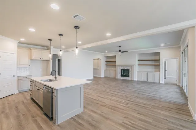 a large kitchen with a stove kitchen island wooden floor center island and cabinets
