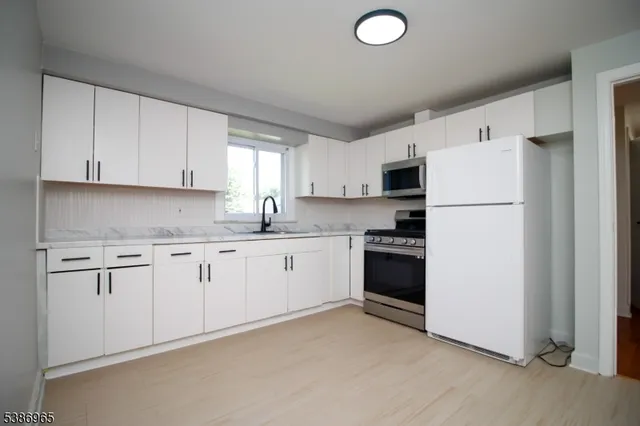 a kitchen with granite countertop white cabinets and white appliances