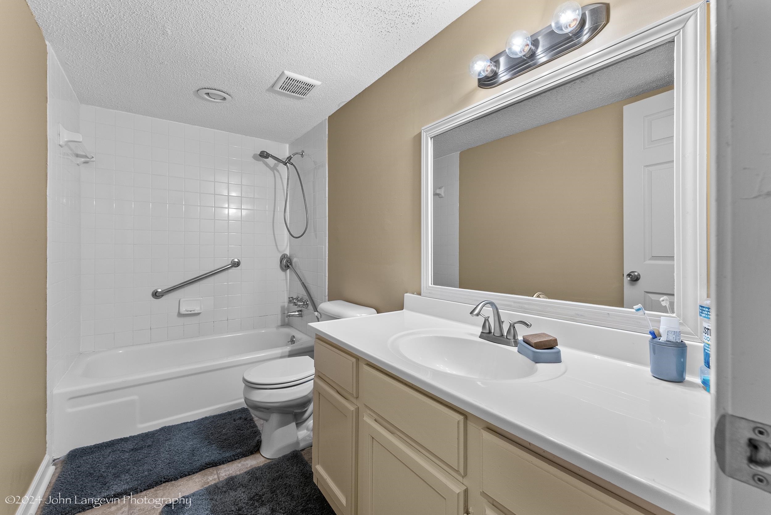 3118 Knob Hill Road Lakeland, TN 38002 - Photo 17 of 27 Full bathroom with tiled shower / bath, a textured ceiling, toilet, and vanity
