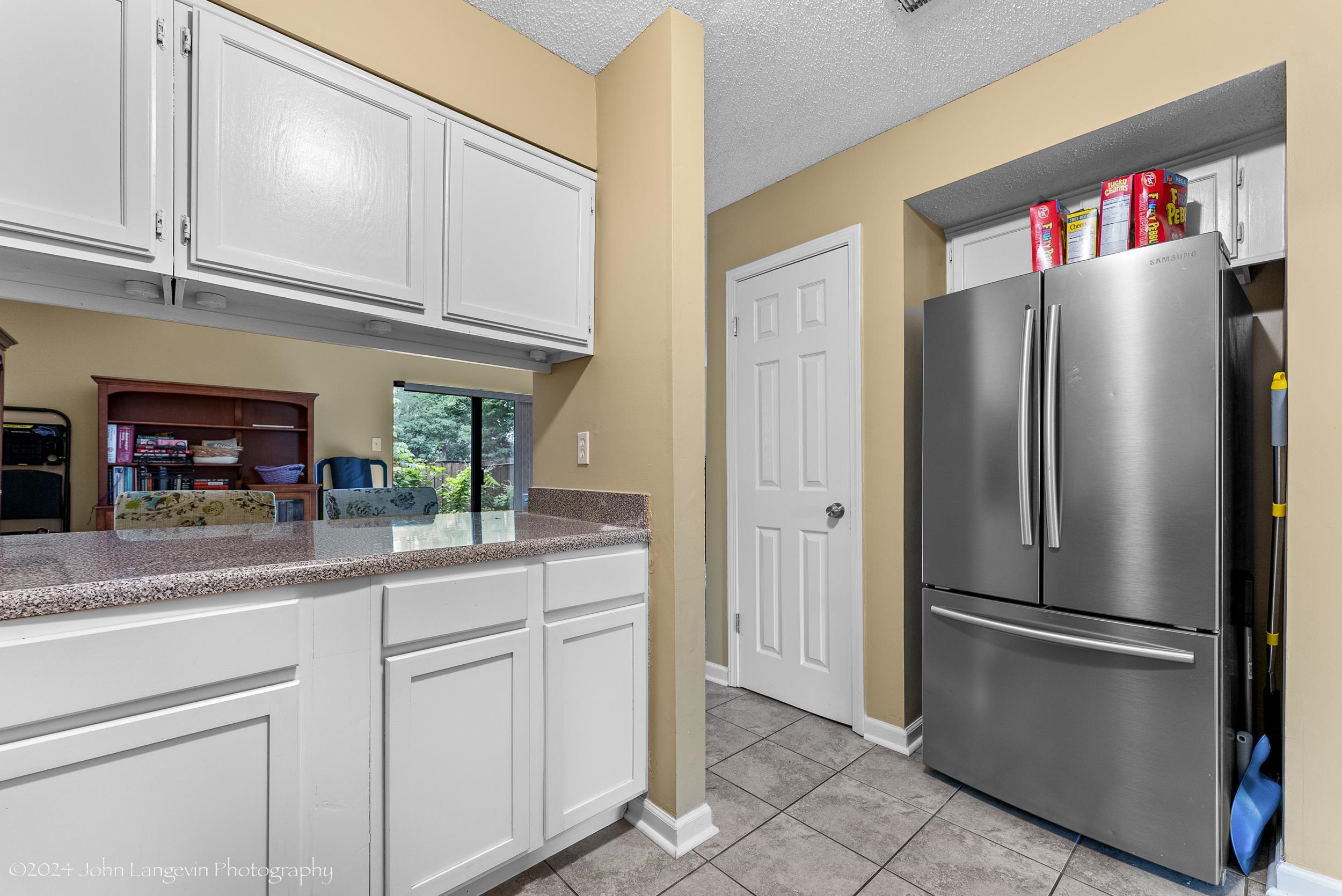 3118 Knob Hill Road Lakeland, TN 38002 - Photo 9 of 27 Kitchen featuring a textured ceiling, stainless steel fridge, white cabinets, stone countertops, and light tile floors