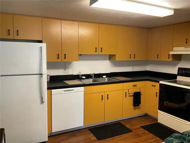 a kitchen with stainless steel appliances granite countertop a refrigerator a stove and a sink with wooden cabinets