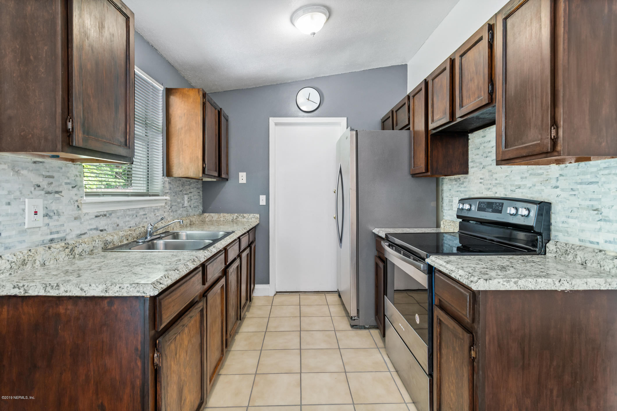 7163 Melvin Road Jacksonville, FL 32210 - Photo 13 of 33 a kitchen with granite countertop a sink stove and refrigerator