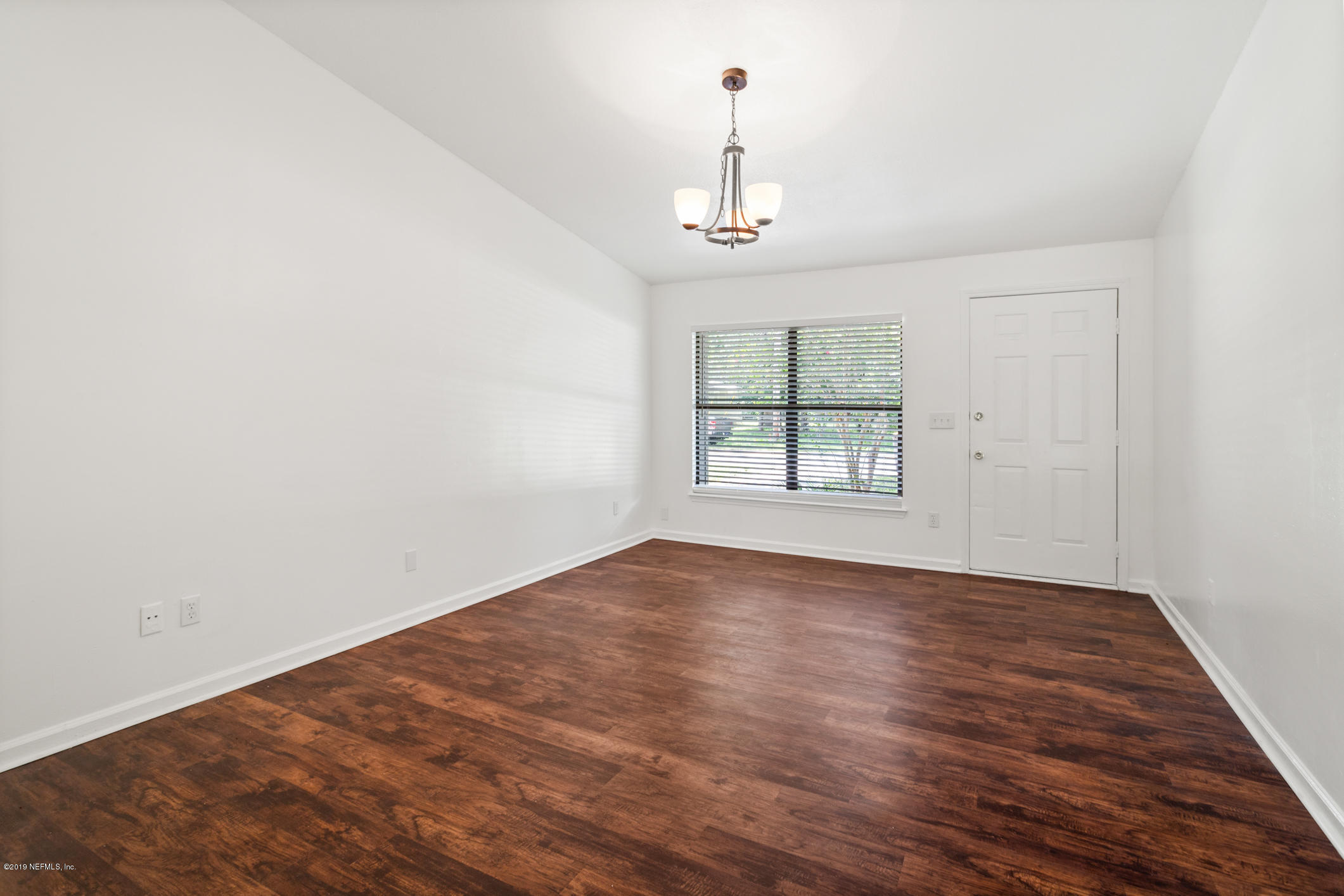 7163 Melvin Road Jacksonville, FL 32210 - Photo 10 of 33 an empty room with wooden floor chandelier and windows