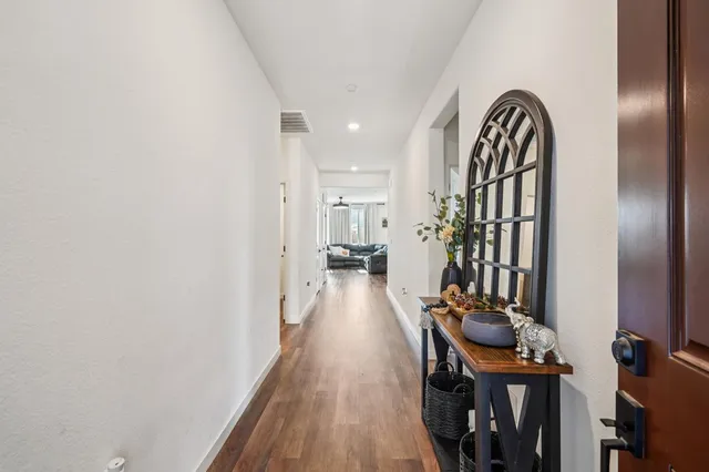 a view of a hallway with wooden floor and a bathroom