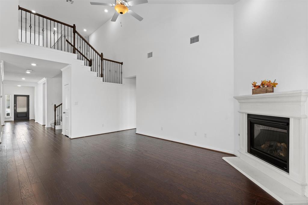 236 Prato Place Georgetown, TX 78628 - Photo 12 of 40 A spacious living room features rich wood flooring, a striking fireplace, and an elegant staircase with wrought iron balusters.