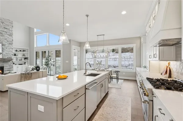 a kitchen with a stove a sink a refrigerator and chairs
