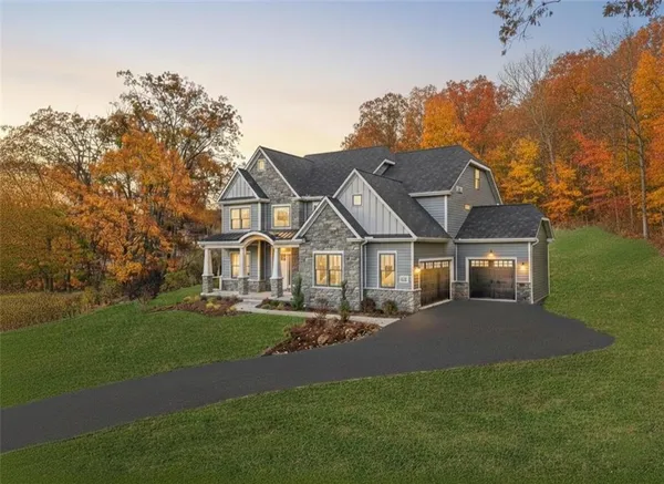 a view of house with a big yard and large trees