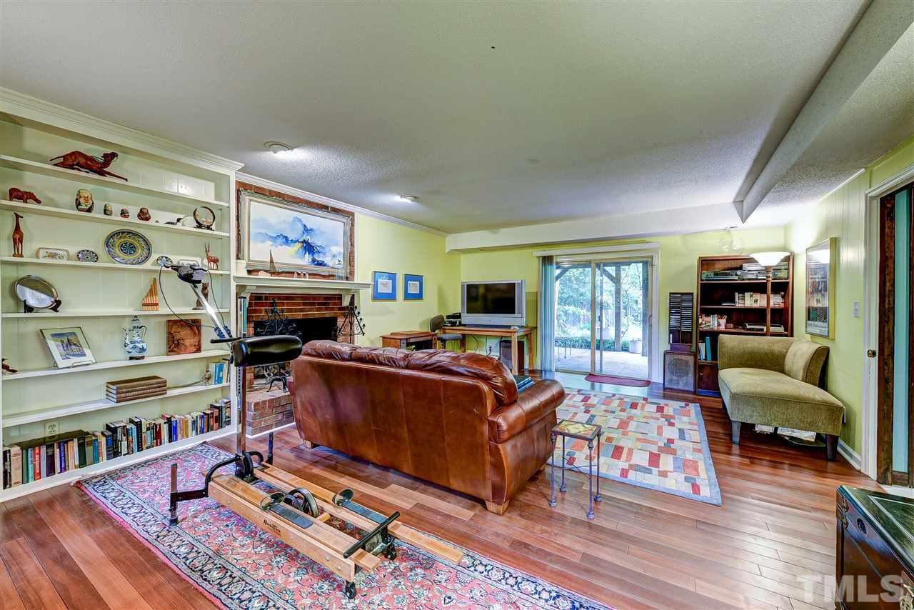 6712 Perkins Drive Raleigh, NC 27612 - Photo 21 of 30 Family Room has open pass from wet bar, bookcases, fireplace, Brazilian cherry flooring, two windows and sliding glass door out to patio. 24 x 16'3