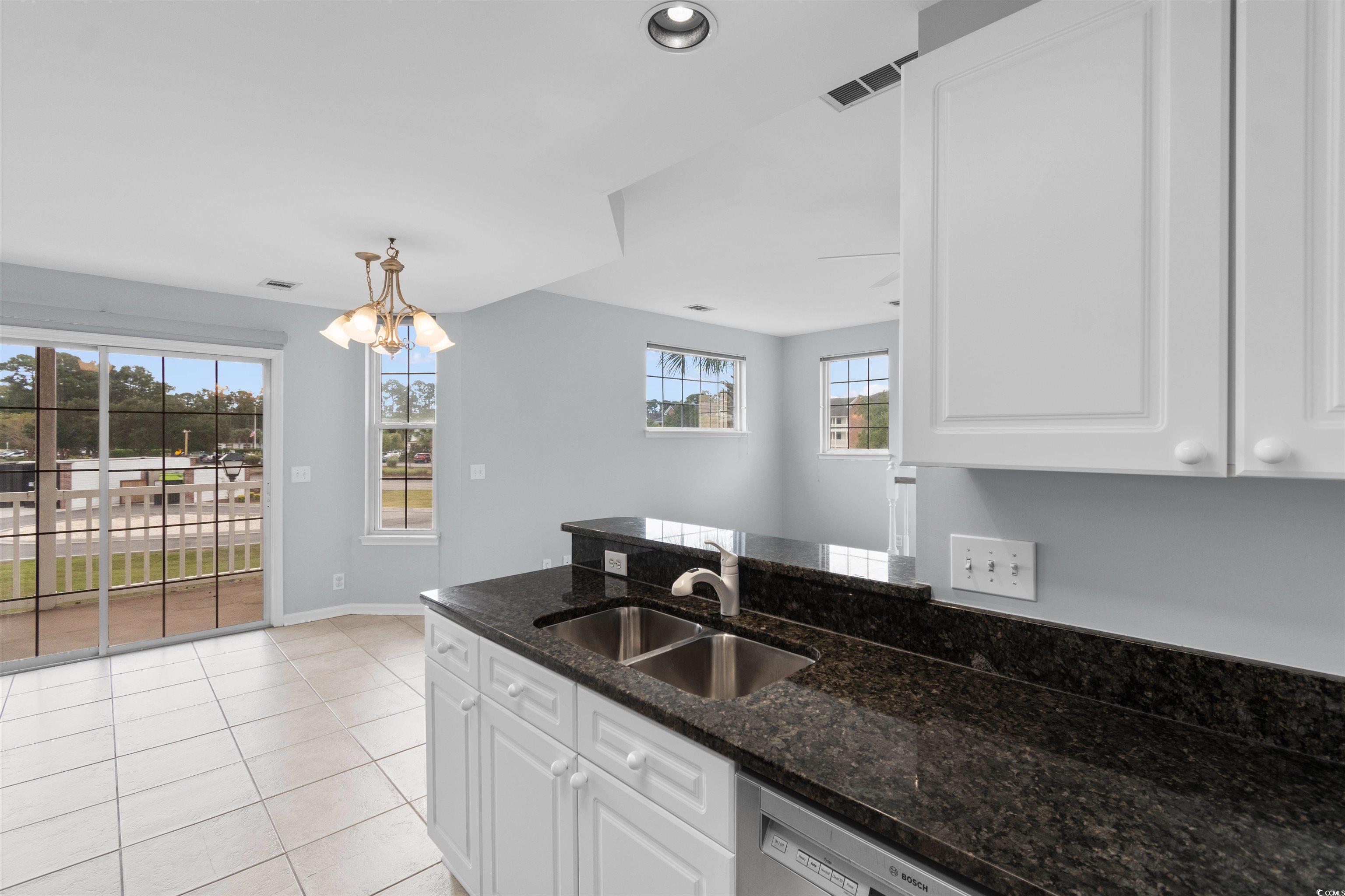 4430 Lady Banks Lane, Unit A2 Murrells Inlet, SC 29576 - Photo 12 of 31 Kitchen with white cabinets, dark stone counters, light tile patterned floors, a chandelier, and a peninsula