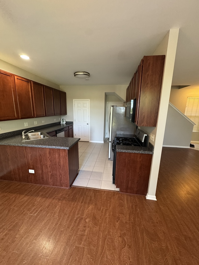 1401 Millbrook Drive Algonquin, IL 60102 - Photo 2 of 14 a kitchen with stainless steel appliances granite countertop a refrigerator a stove and a sink with wooden floor