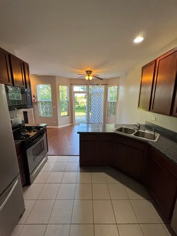 a kitchen with granite countertop a stove a sink and a refrigerator
