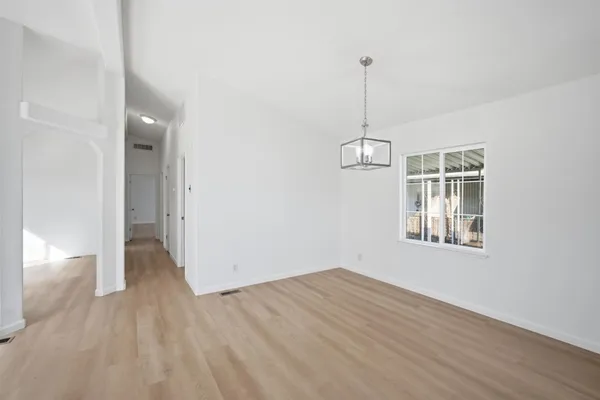 a view of empty room with wooden floor and ceiling fan