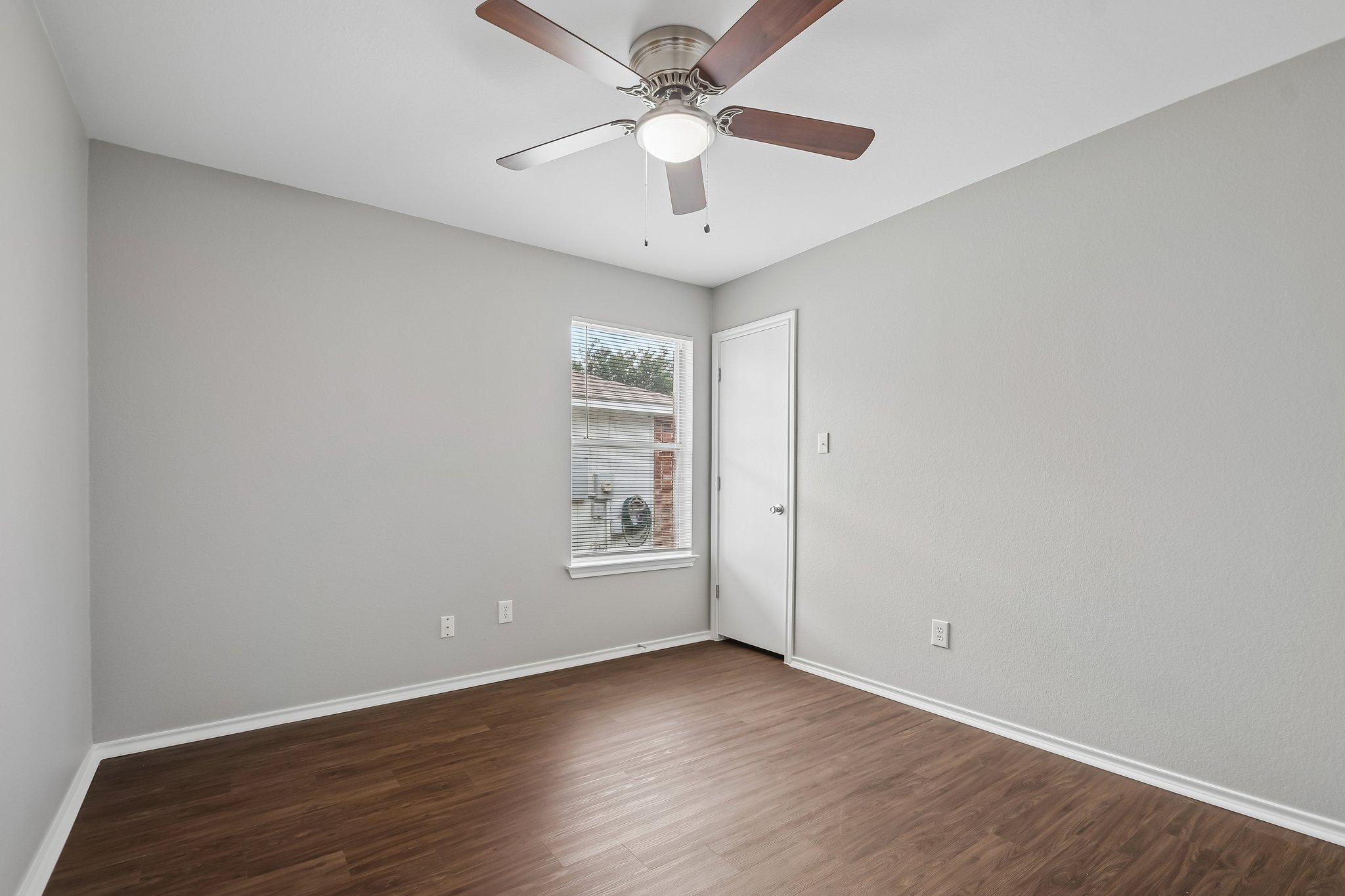 610 Lavaca Loop Elgin, TX 78621 - Photo 27 of 37 A well-lit bedroom with rich wood flooring features a contemporary ceiling fan and a window with blinds.