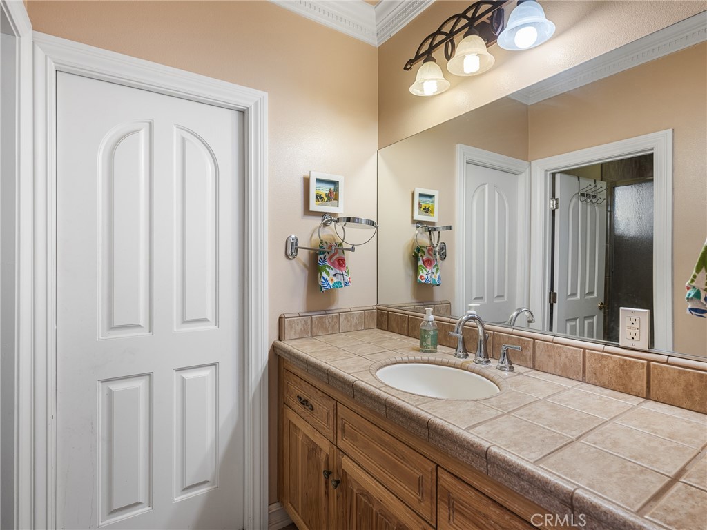 7139 Foley Road Oak Hills, CA 92344 - Photo 34 of 72 a bathroom with a granite countertop sink a light fixture and a mirror