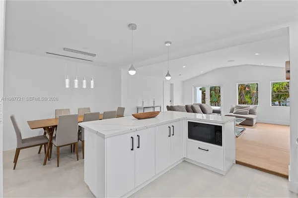 a large white kitchen with stainless steel appliances kitchen island granite countertop a table and chairs