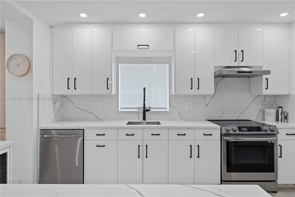 a kitchen with stainless steel appliances granite countertop a sink a stove and a refrigerator