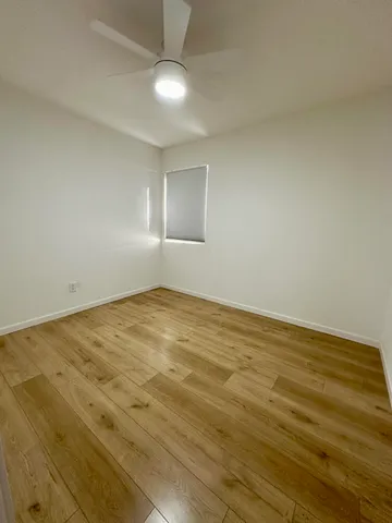 an empty room with wooden floor and fan