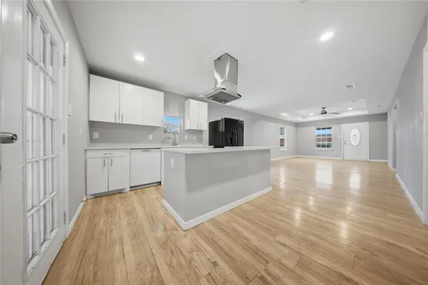 a view of a kitchen with kitchen island a sink wooden floor and stainless steel appliances