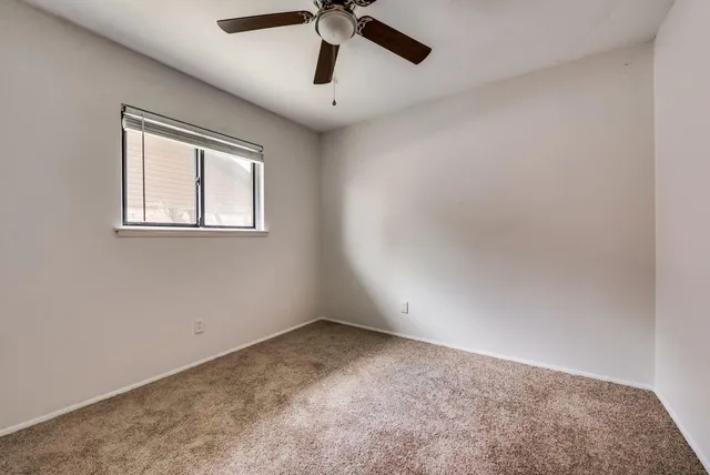 en empty room with windows and ceiling fan