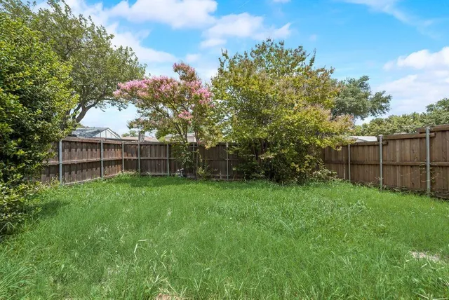 a view of backyard with wooden fence and trees