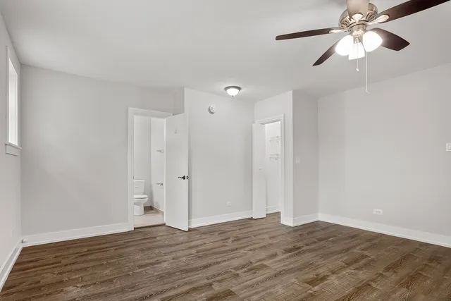 a view of an empty room with wooden floor and a ceiling fan