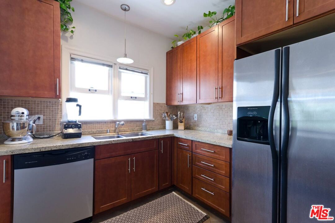 506 North Spaulding Avenue Los Angeles, CA 90036 - Photo 10 of 23 a kitchen with stainless steel appliances granite countertop a sink a refrigerator and wooden cabinets