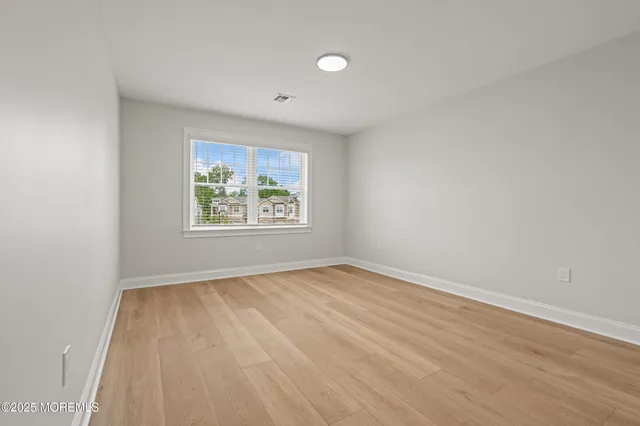 an empty room with wooden floor and window