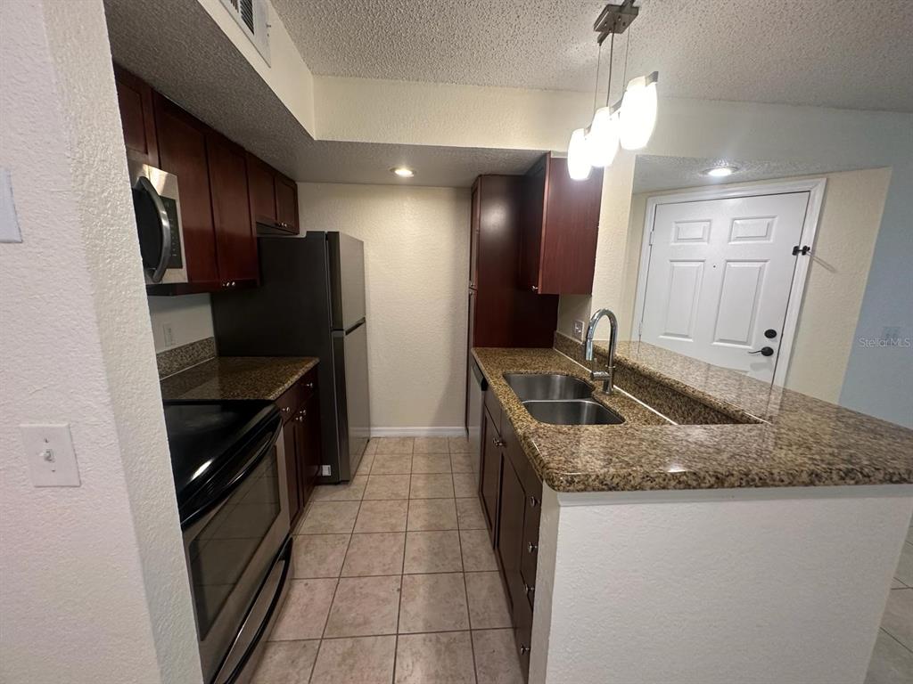 5120 Conroy Road, Unit 13 Orlando, FL 32811 - Photo 5 of 21 a kitchen with kitchen island granite countertop a sink stove and refrigerator