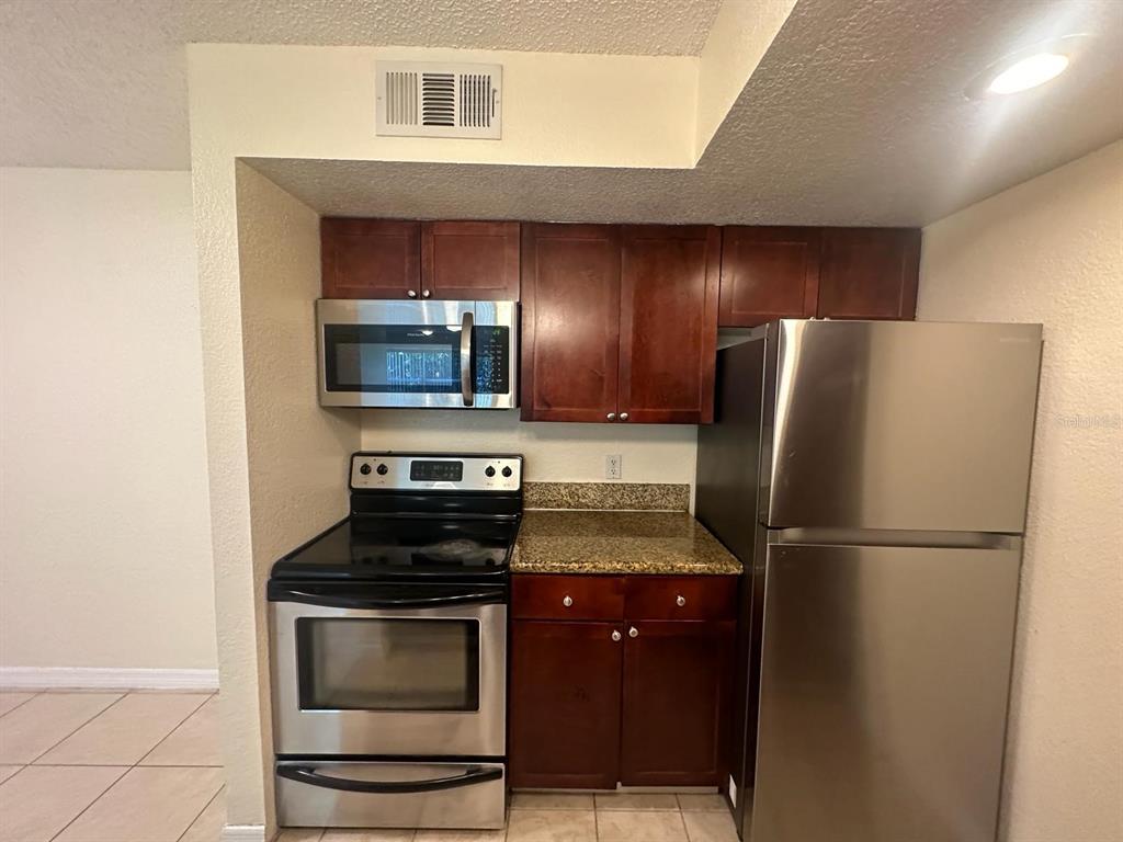 5120 Conroy Road, Unit 13 Orlando, FL 32811 - Photo 6 of 21 a kitchen with a refrigerator and a stove top oven