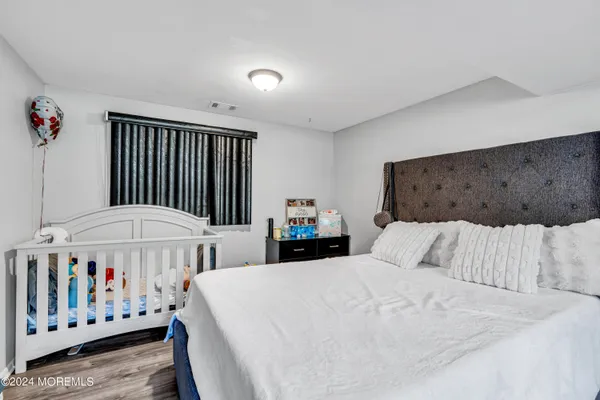 a bedroom with a bed a table and a dresser next to a window