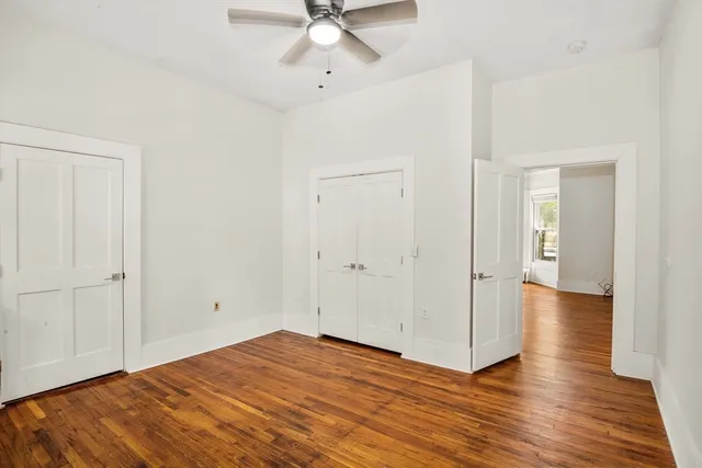 an empty room with wooden floor and ceiling fan