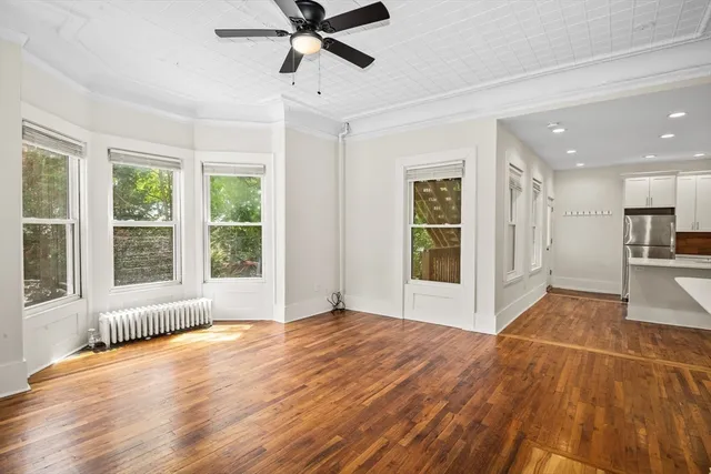 a view of an empty room with wooden floor and a window