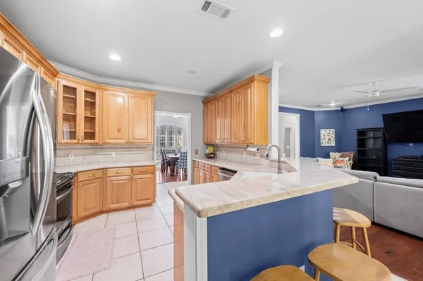 a large kitchen with stainless steel appliances kitchen island granite countertop a refrigerator a stove a sink a dining table and chairs with wooden floor