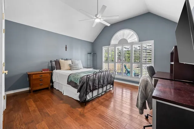 a bedroom with a bed a desk and chair with wooden floor