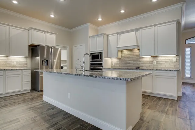 a kitchen with kitchen island granite countertop a sink cabinets and stainless steel appliances